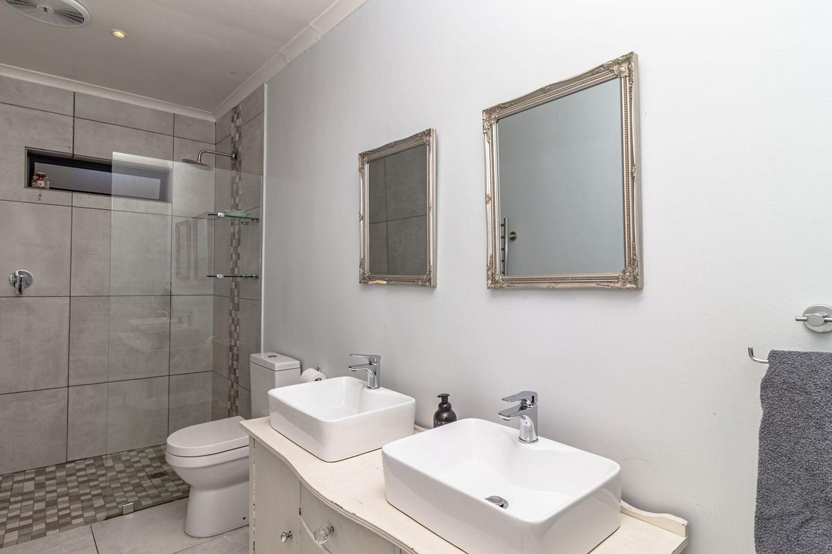 Modern bathroom featuring a double vanity with vessel sinks, a glass-enclosed walk-in shower with tiled walls, and contemporary fixtures.