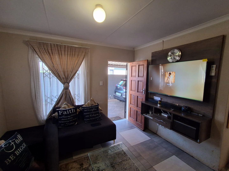 A cozy living room featuring a built-in media console, tiled flooring, and direct access to the exterior driveway area.