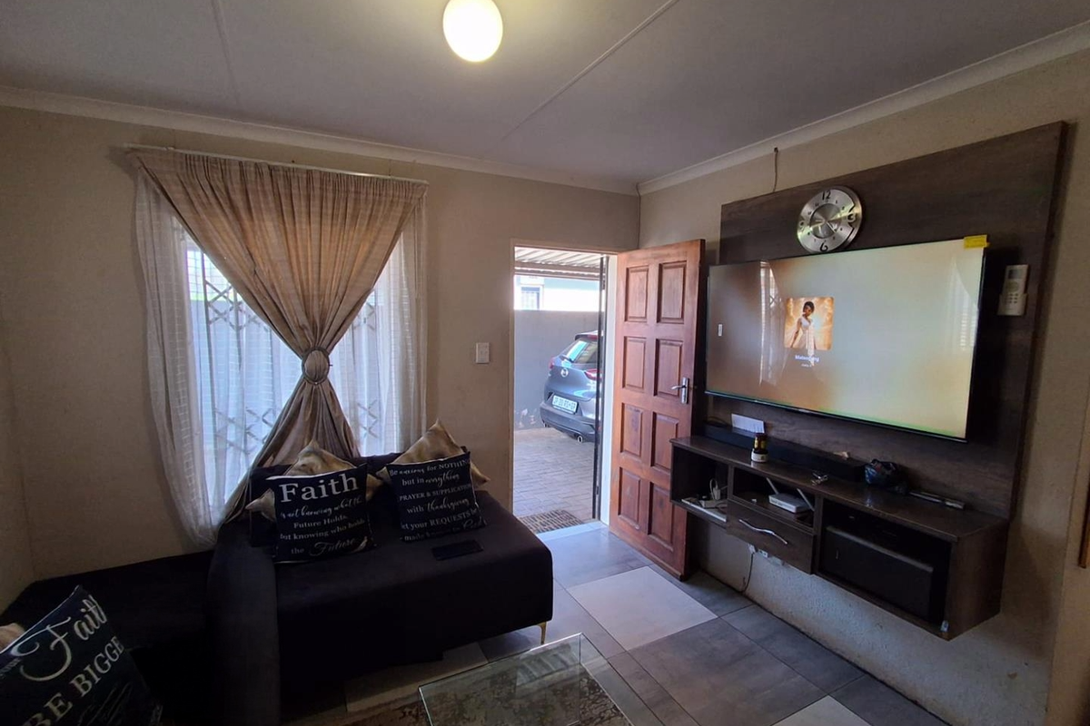 A cozy living room featuring a built-in media console, tiled flooring, and direct access to the exterior driveway area.