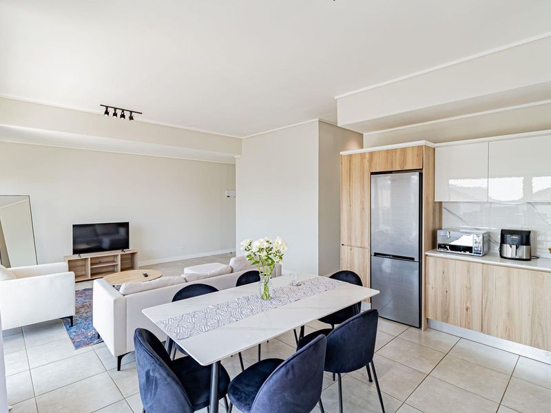 Modern open-plan living and dining area featuring tiled floors, contemporary cabinetry, and integrated kitchen appliances in a bright, well-maintained penthouse space.