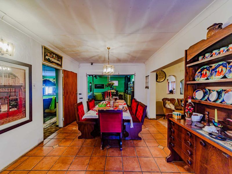 A dining room featuring terracotta floor tiles and an archway leading to adjacent living spaces, with visible water staining on the ceiling.