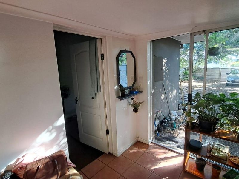 An entry area featuring tiled flooring and a sliding glass door providing direct access to the exterior garden and driveway.