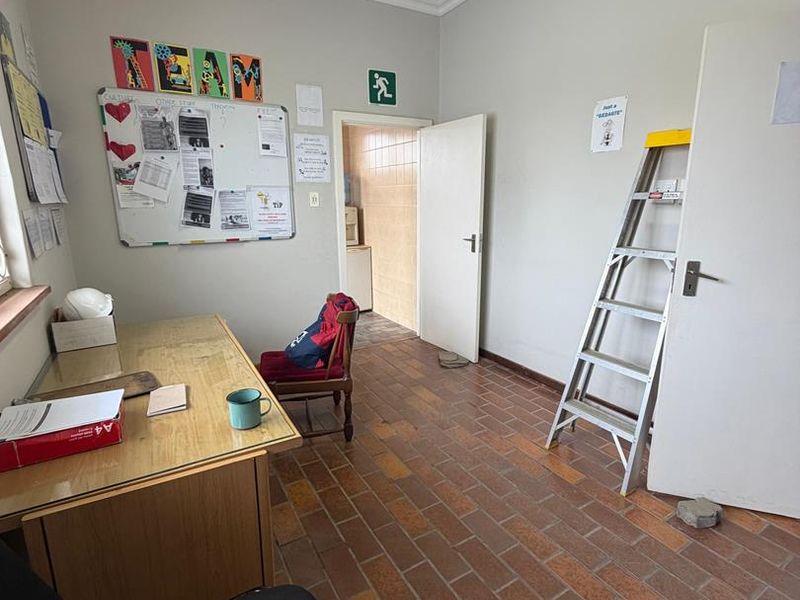 A functional office space featuring terracotta tile flooring, neutral walls, and a standard ceiling light fixture, providing a practical workspace environment.