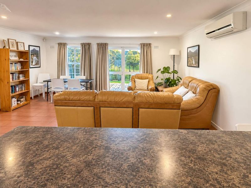 Spacious open-plan living and dining area featuring tiled floors, split-system air conditioning, and direct access to the rear patio through glass doors.