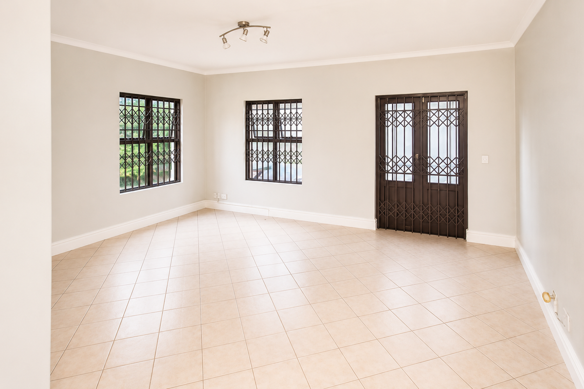 A bright, empty living room featuring neutral tiled flooring, security gates on the doors and windows, and clean, well-maintained wall finishes.
