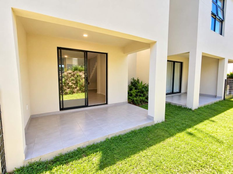 A modern covered patio featuring tiled flooring and recessed lighting, providing seamless access to the garden through large sliding glass doors.