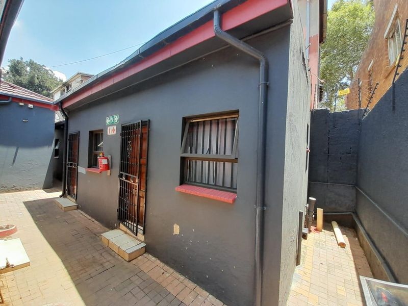 Rear exterior view of the property featuring dark painted walls, security gates, and paved outdoor walkway area.