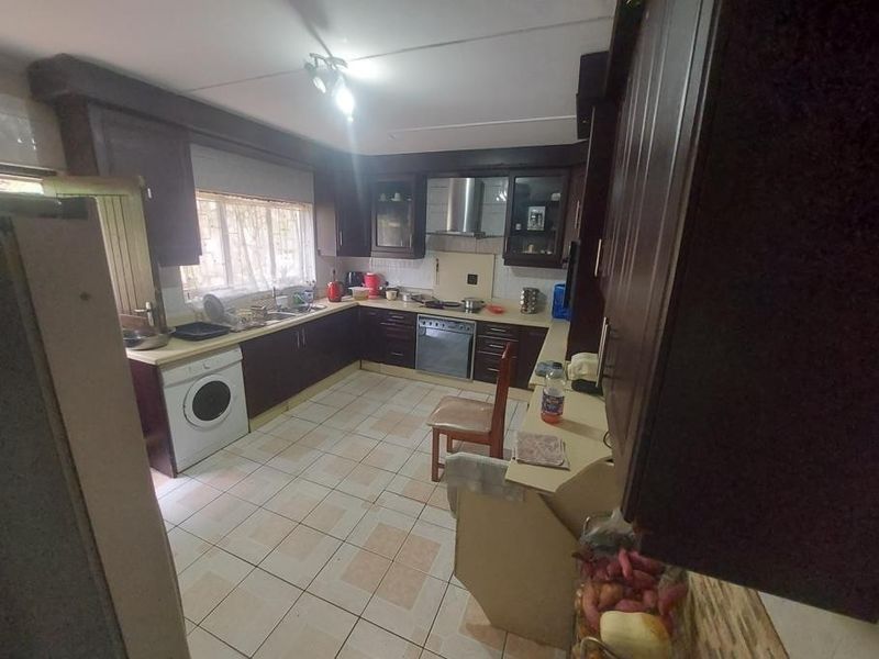A functional kitchen featuring dark wood cabinetry, stainless steel appliances, tiled flooring, and ample counter space, offering potential for a modern cosmetic update.