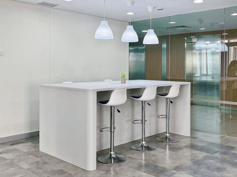Modern office breakout area featuring a sleek built-in island counter, contemporary pendant lighting, and glass partition walls for a professional, open-plan workspace.