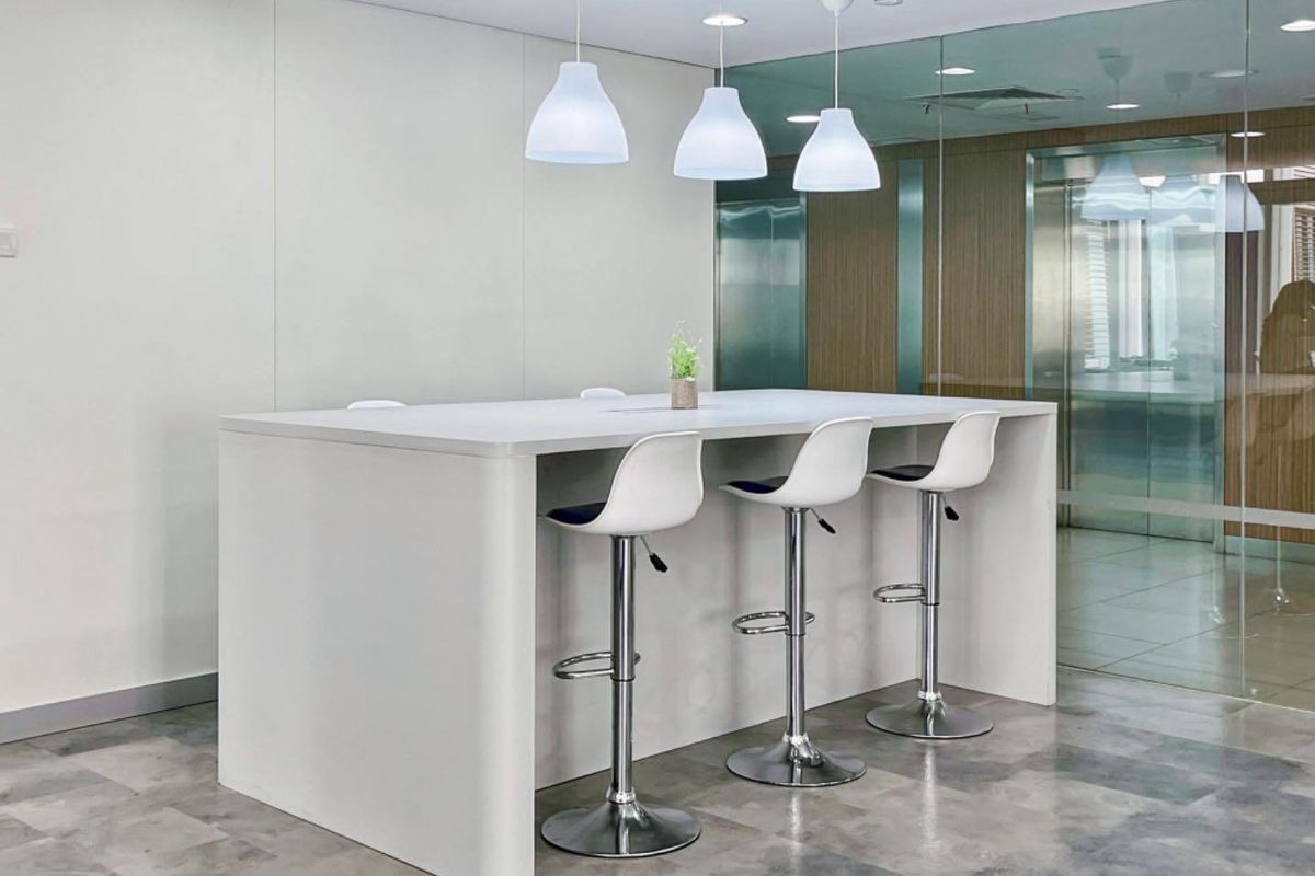 Modern office breakout area featuring a sleek built-in island counter, contemporary pendant lighting, and glass partition walls for a professional, open-plan workspace.