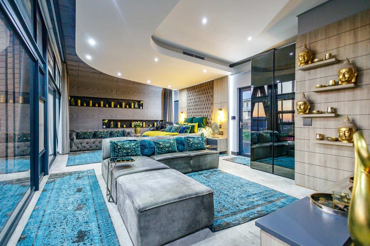 A spacious, modern bedroom featuring a unique curved recessed ceiling with integrated lighting, floor-to-ceiling glass walls, and custom built-in cabinetry with mirrored finishes.