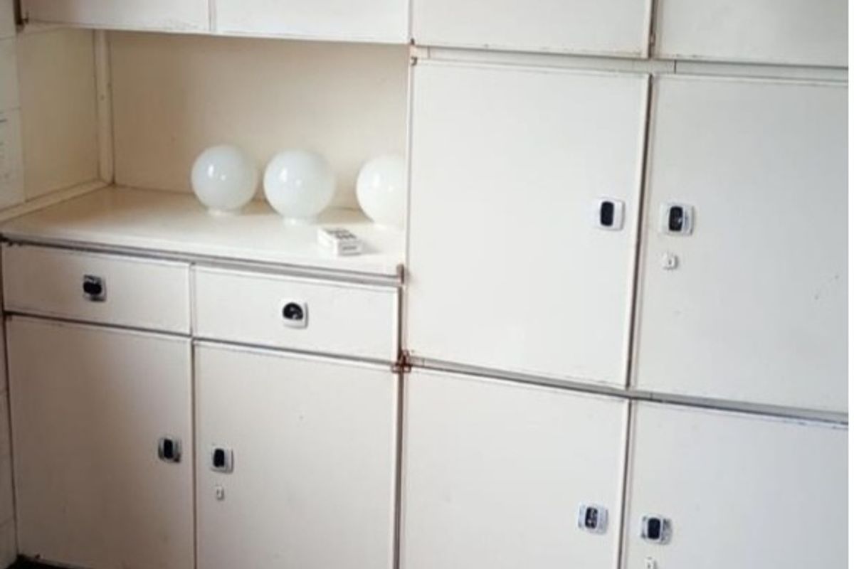 A dated kitchen area featuring original built-in cabinetry and retro-style vinyl tile flooring, offering significant potential for modernization and renovation.