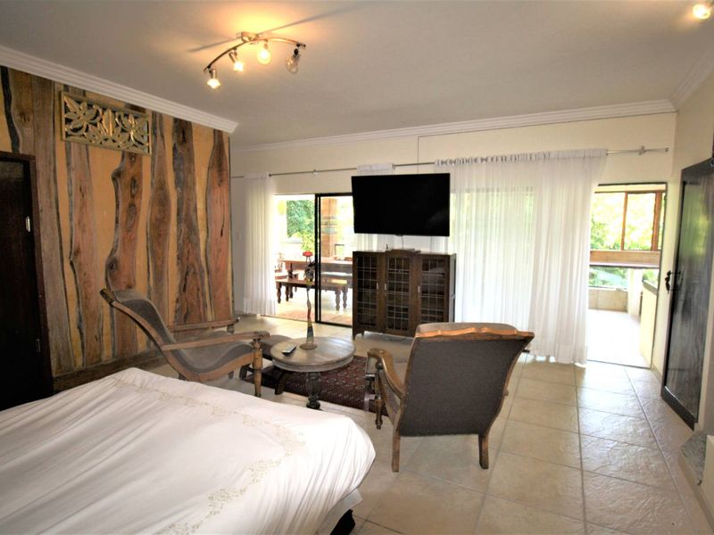 Spacious bedroom featuring tiled flooring, decorative wood wall paneling, and large sliding glass doors providing access to an outdoor patio area.