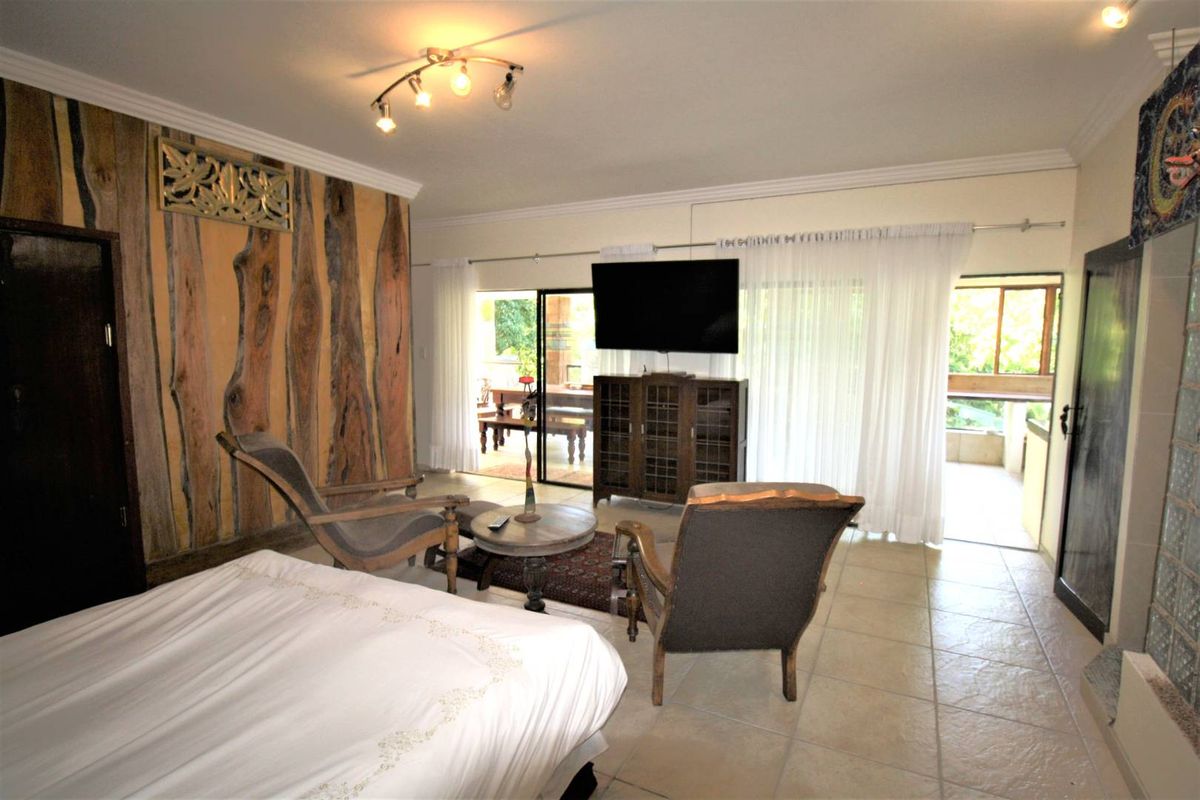 Spacious bedroom featuring tiled flooring, decorative wood wall paneling, and large sliding glass doors providing access to an outdoor patio area.