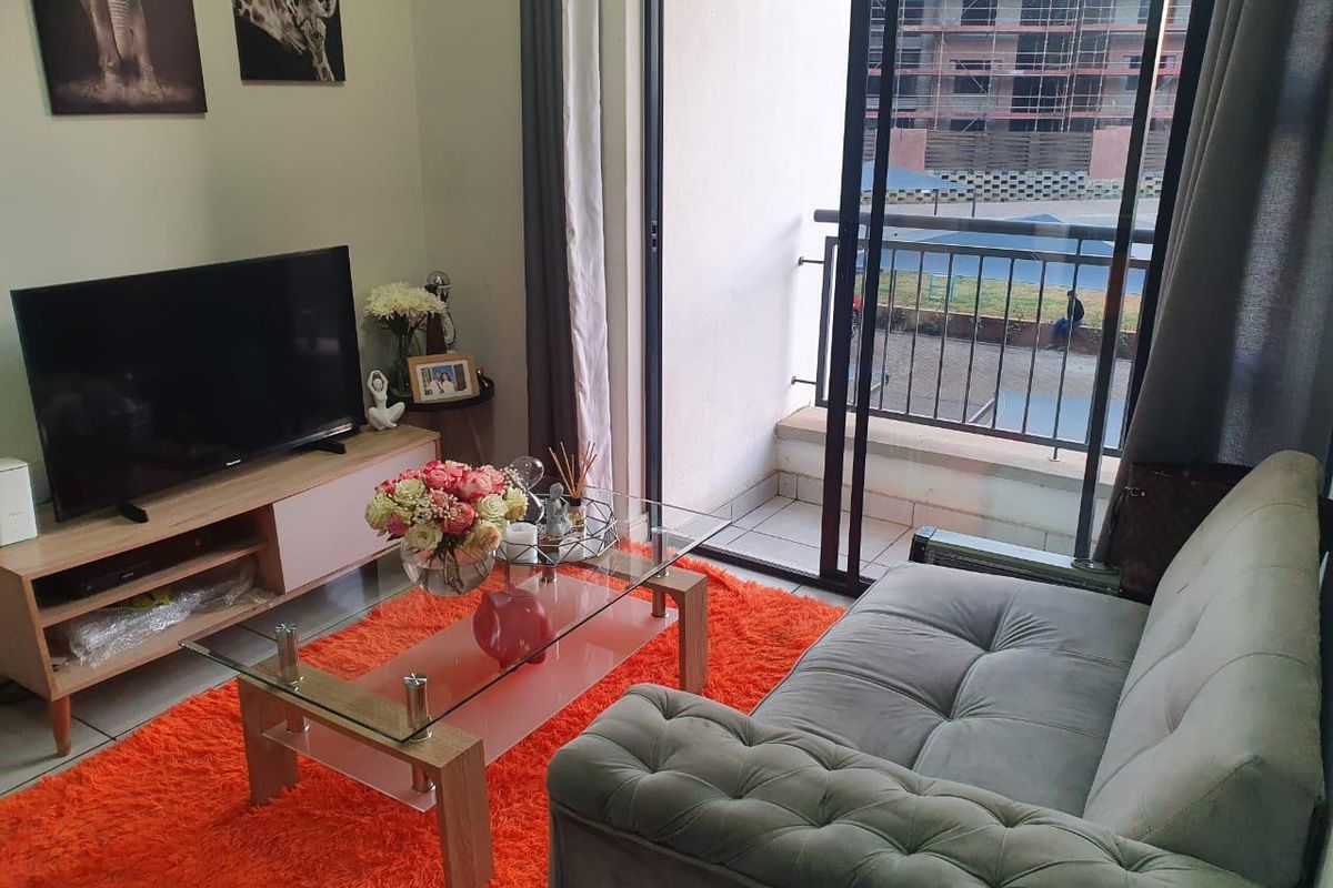 A comfortable living room featuring a sliding glass door that opens onto a private balcony with metal railings.