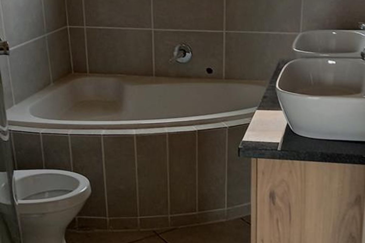 A functional bathroom featuring a corner bathtub, vanity with vessel sink, toilet, and a separate shower enclosure with tiled finishes.