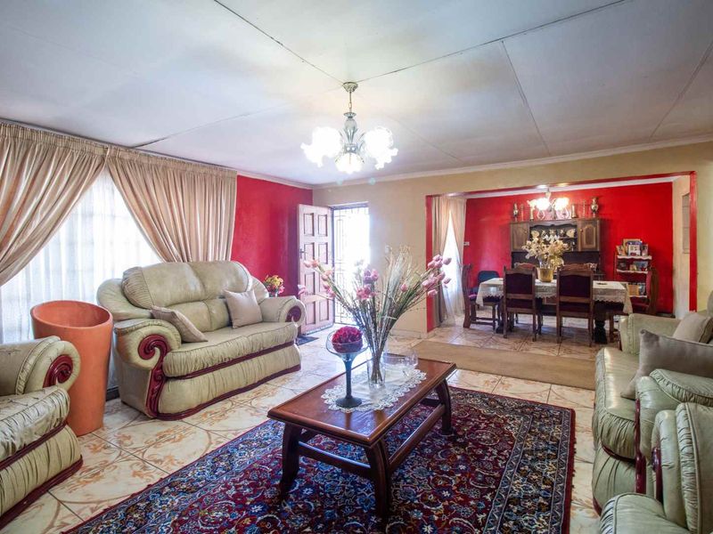 Open-plan living and dining area featuring ceramic floor tiles, a central chandelier, and direct access to the entrance.