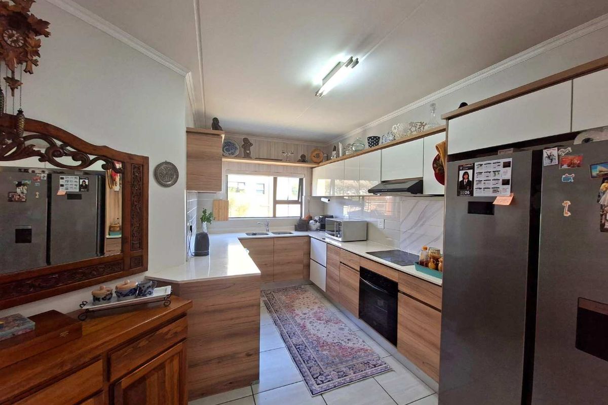 Modern kitchen featuring wood-grain cabinetry, white countertops, integrated appliances, and tiled flooring, offering a functional and well-maintained workspace.
