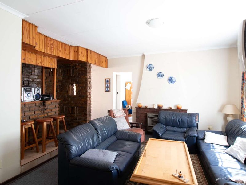 A living room featuring a prominent brick fireplace and a built-in brick bar with timber detailing, offering a dated aesthetic ready for modernization.