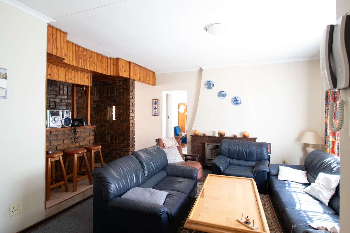 A living room featuring a prominent brick fireplace and a built-in brick bar with timber detailing, offering a dated aesthetic ready for modernization.