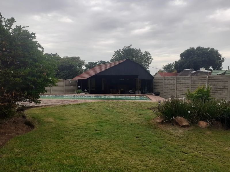 Spacious backyard featuring a swimming pool, paved surround, and a covered lapa area, enclosed by high brick boundary walls.