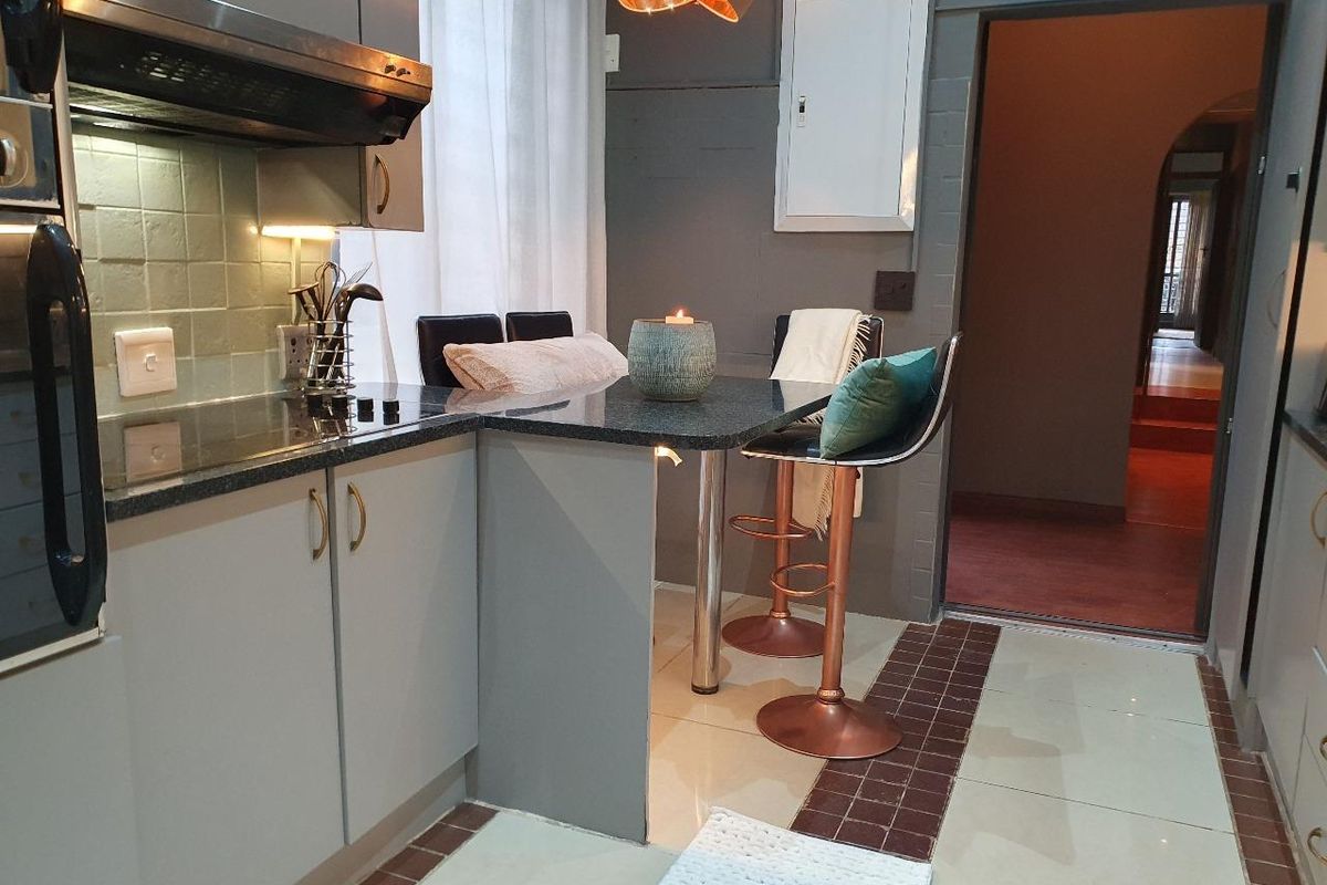 Modern kitchen featuring grey cabinetry, dark granite countertops, a built-in oven, extractor fan, and a convenient breakfast bar area.