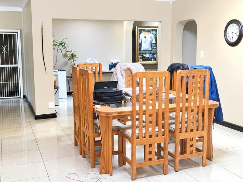 A dining area featuring neutral walls, tiled flooring, and an arched entryway leading to an adjacent space.