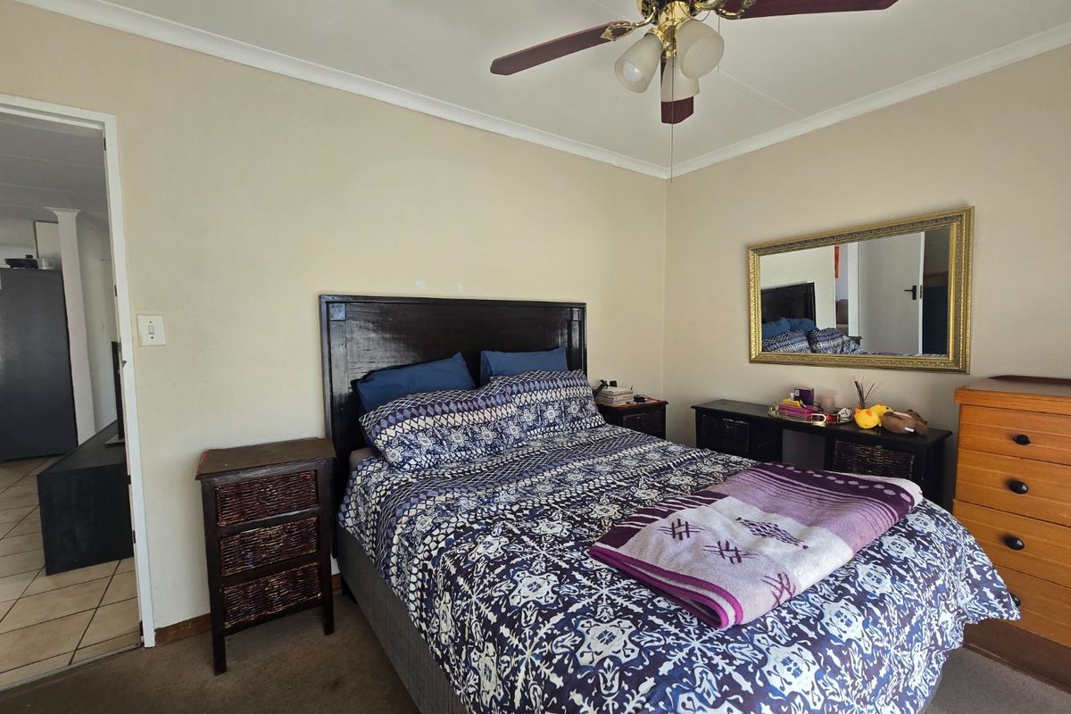 A standard bedroom featuring a ceiling fan, neutral wall finishes, and carpet flooring, offering a functional space ready for cosmetic updates.