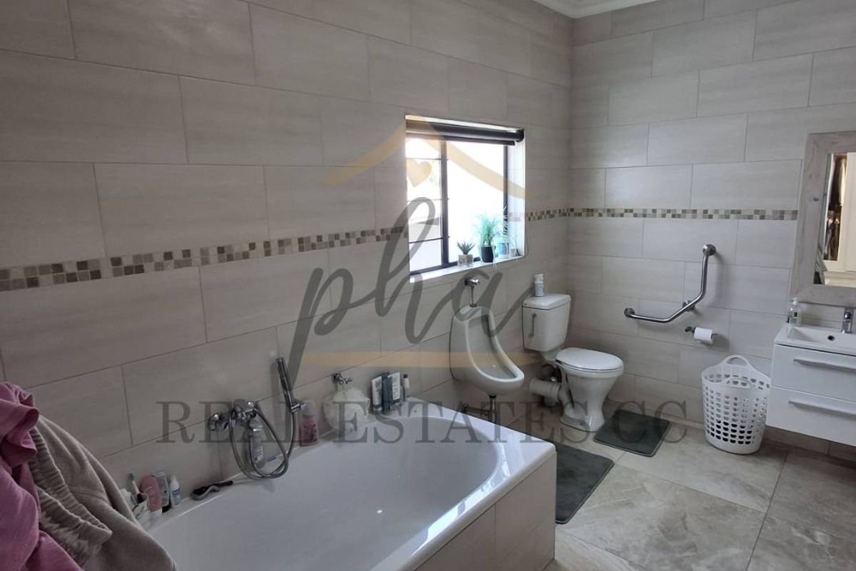 A well-maintained bathroom featuring a built-in bathtub, wall-mounted toilet, urinal, and a modern vanity with a mirror.