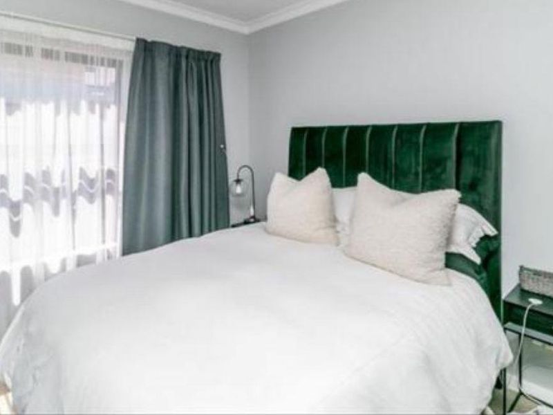 A well-maintained bedroom featuring neutral wall tones, crown molding, and a sliding glass door providing natural light.