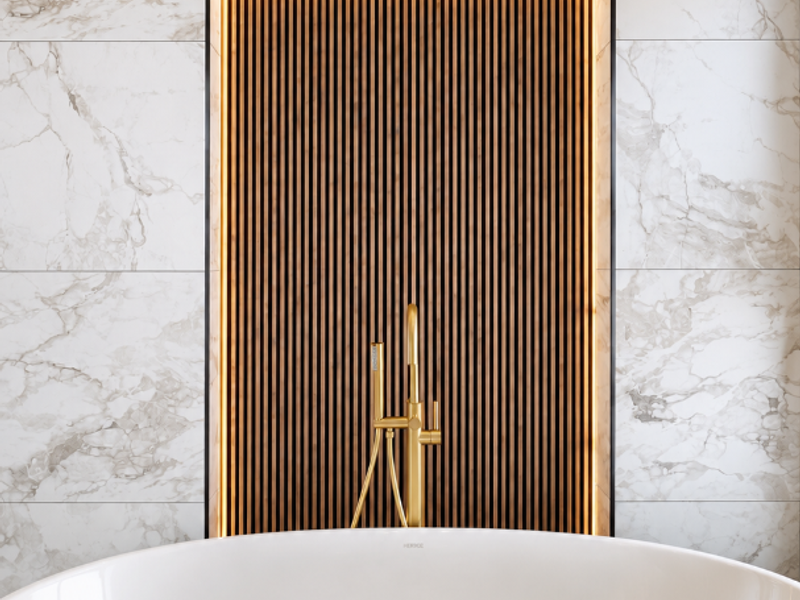 A luxurious bathroom featuring a modern freestanding bathtub, brass fixtures, and a striking marble-tiled wall with a backlit timber slat feature.