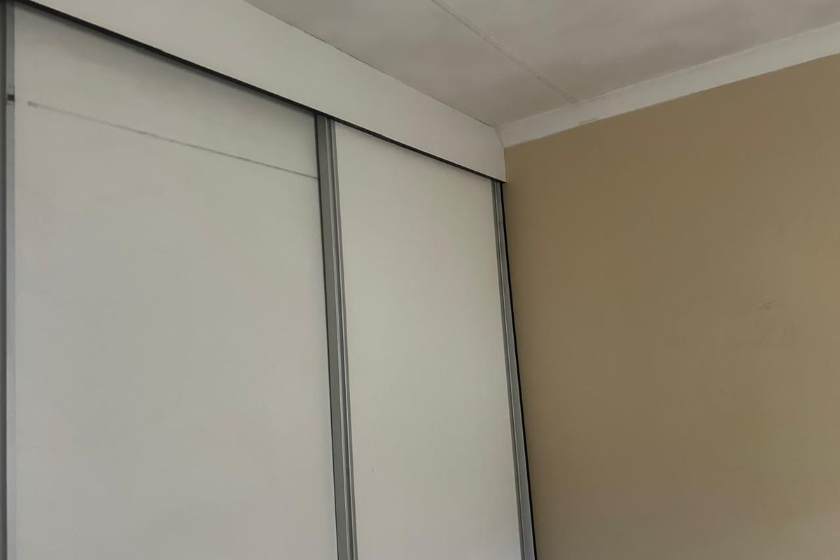 A close-up view of built-in sliding door cupboards featuring a white finish and metal framing.