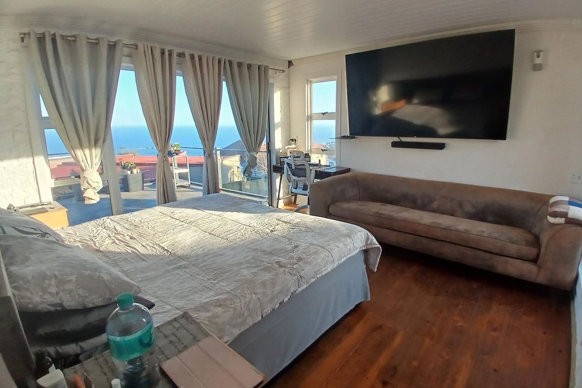 Spacious bedroom featuring hardwood flooring, tongue and groove ceiling, and large sliding glass doors opening to a scenic ocean view.