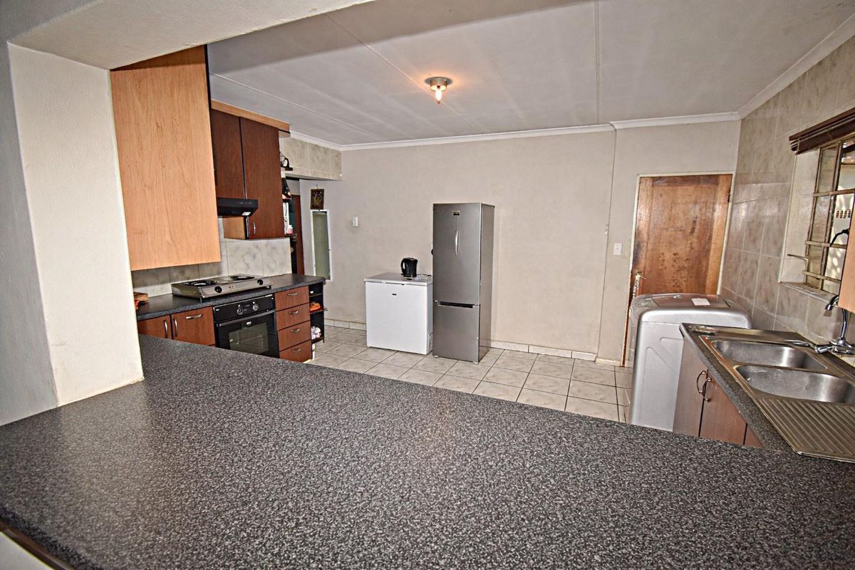 Functional kitchen featuring laminate countertops, built-in oven and hob, double basin sink, and tiled flooring with ample space for appliances.