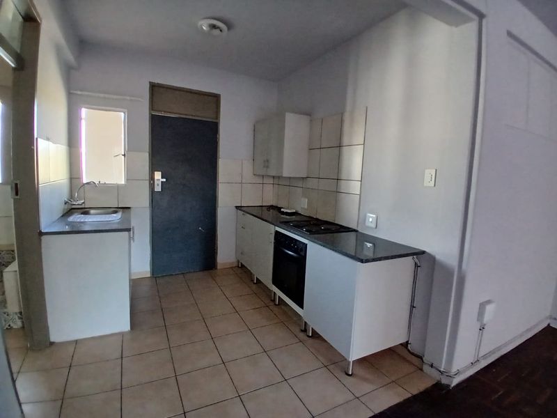 A functional kitchen featuring built-in cabinetry, granite countertops, a built-in oven and hob, and tiled flooring.
