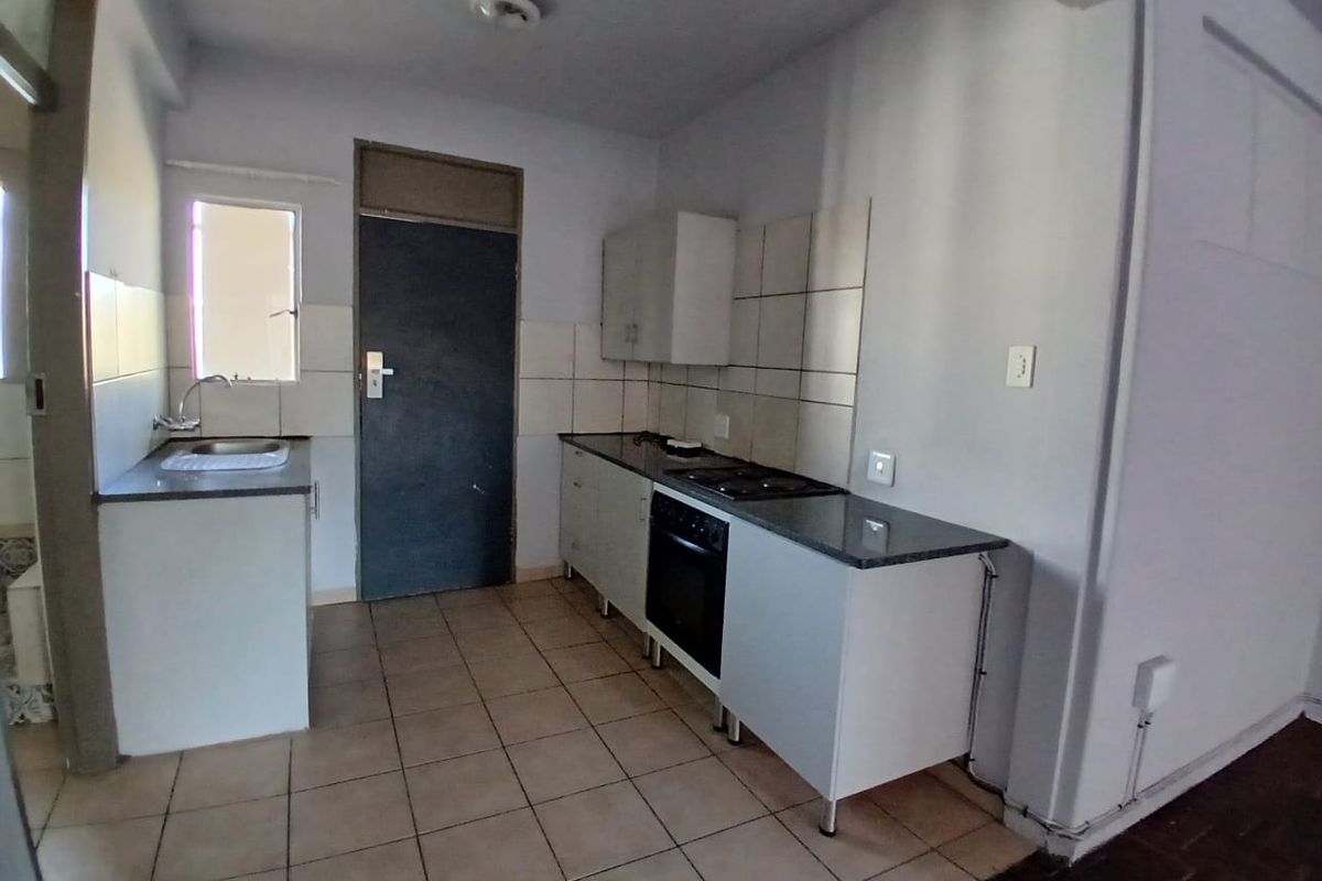 A functional kitchen featuring built-in cabinetry, granite countertops, a built-in oven and hob, and tiled flooring.