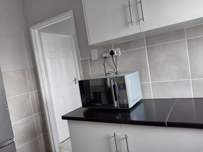 A functional kitchen area featuring white cabinetry, dark countertops, and neutral tiled backsplash, providing a clean and practical workspace.