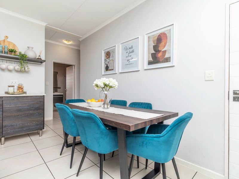 A bright dining area featuring tiled flooring, built-in cabinetry with a floating shelf, and direct access to adjacent rooms.