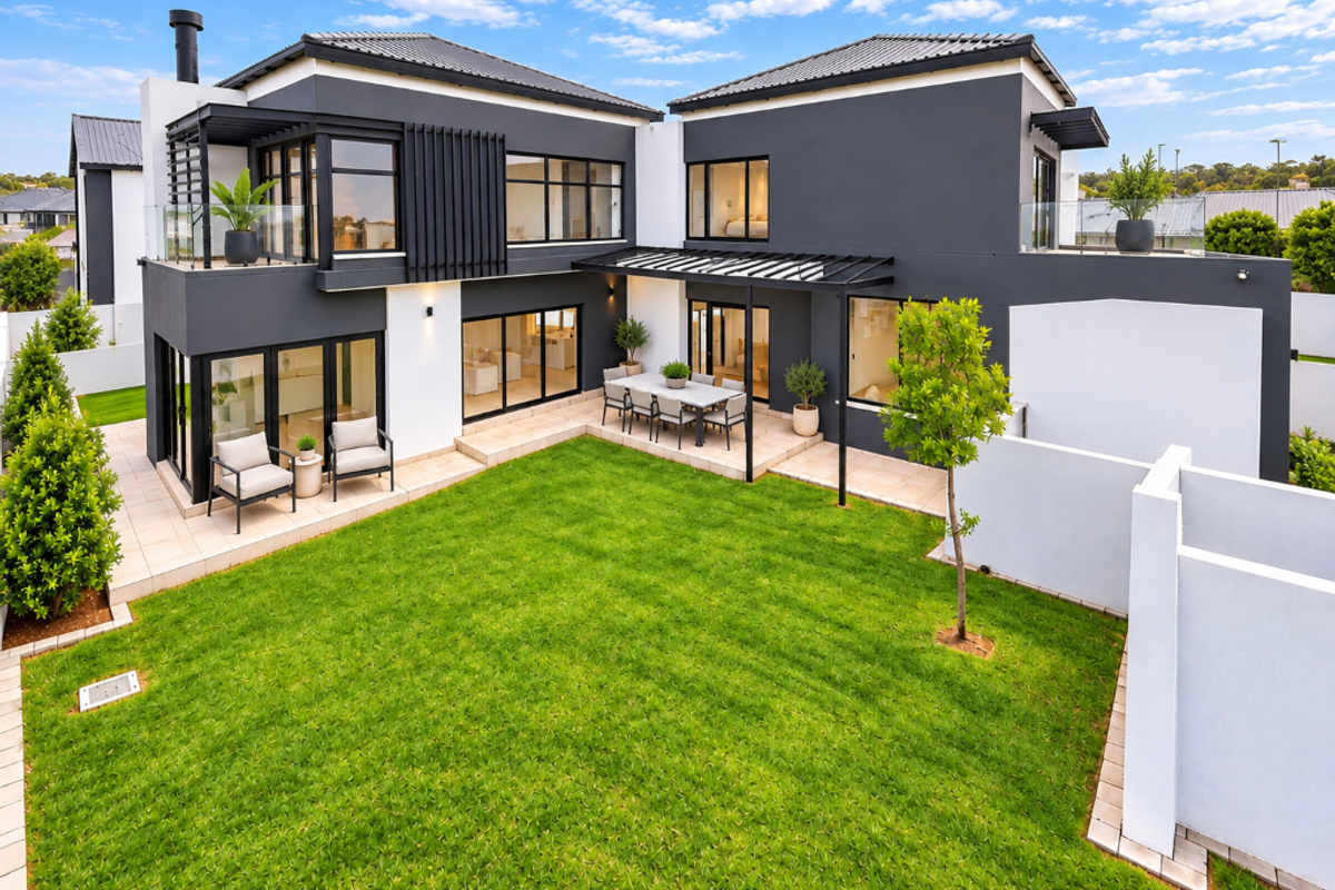 Modern double-story residence featuring a spacious rear garden, tiled patio area with pergola, and large sliding glass doors for seamless indoor-outdoor living.