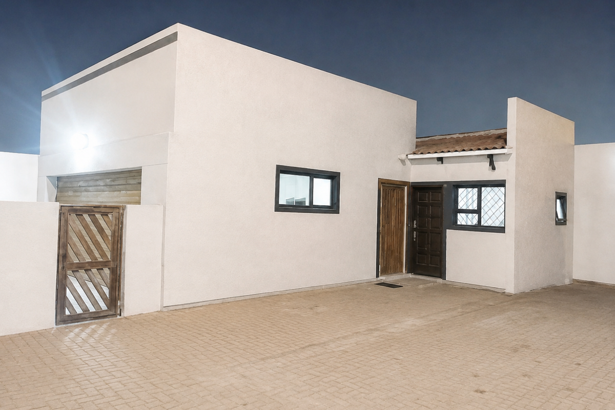 Modern exterior front facade featuring a paved driveway, secure wooden pedestrian gate, and clean white rendered walls with dark aluminium window frames.