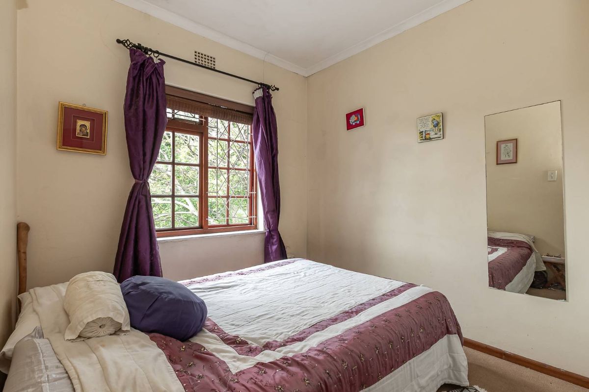 A standard bedroom featuring timber-framed windows with security bars, carpeted flooring, and coved ceiling details.