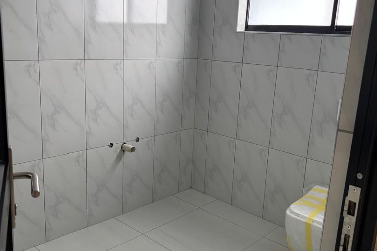 A newly tiled bathroom space featuring marble-effect wall tiles and white floor tiles, currently awaiting the installation of sanitary ware and plumbing fixtures.