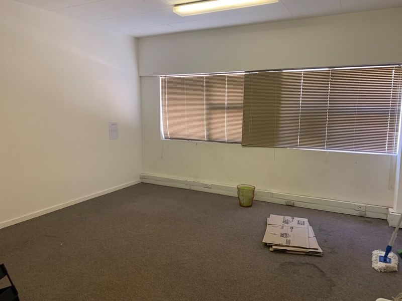 A vacant office space featuring carpet flooring, surface-mounted electrical trunking, and window blinds, offering a blank canvas for professional workspace customization.