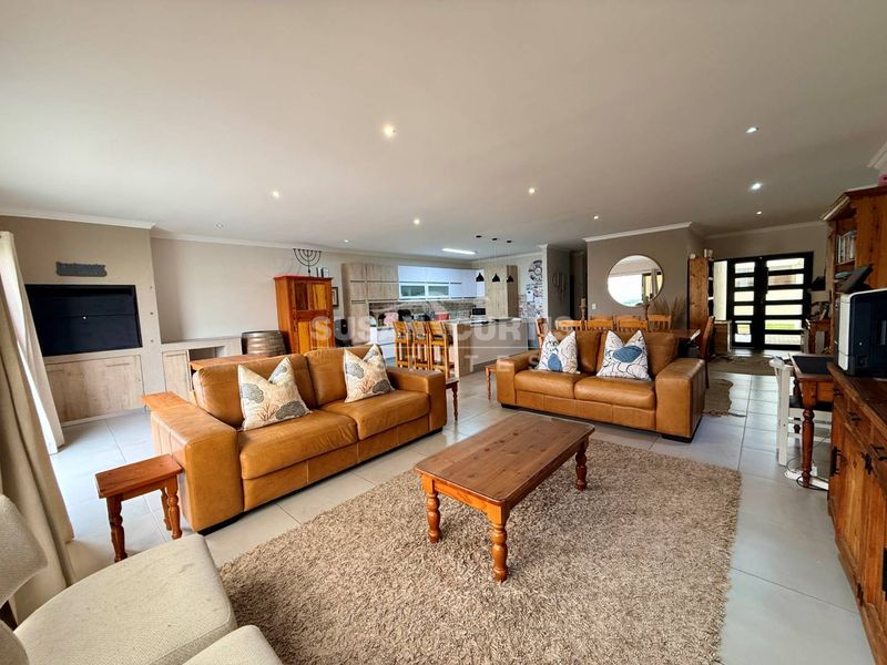 Spacious open-plan living area featuring a modern kitchen with island, tiled floors, recessed lighting, and a built-in fireplace, creating a cohesive family space.