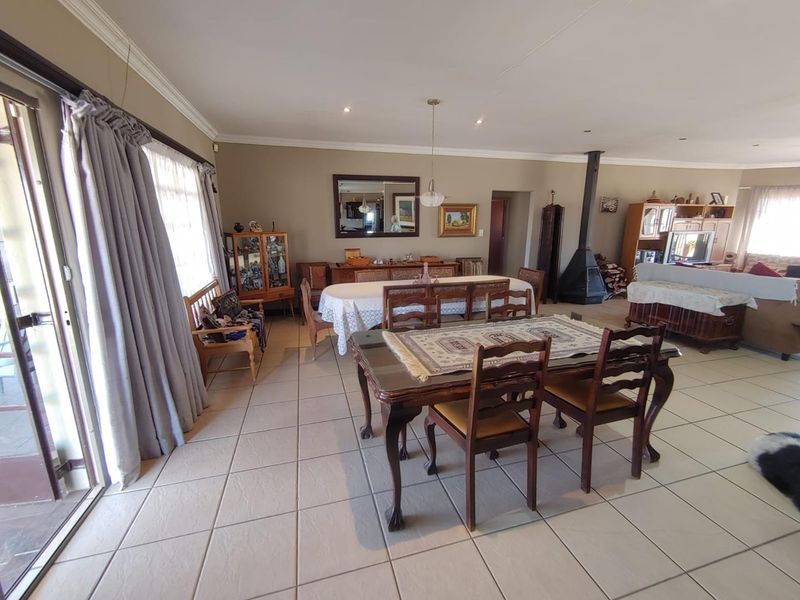 Spacious open-plan living and dining area featuring tiled flooring, a freestanding fireplace, and large sliding doors providing access to the outdoor space.