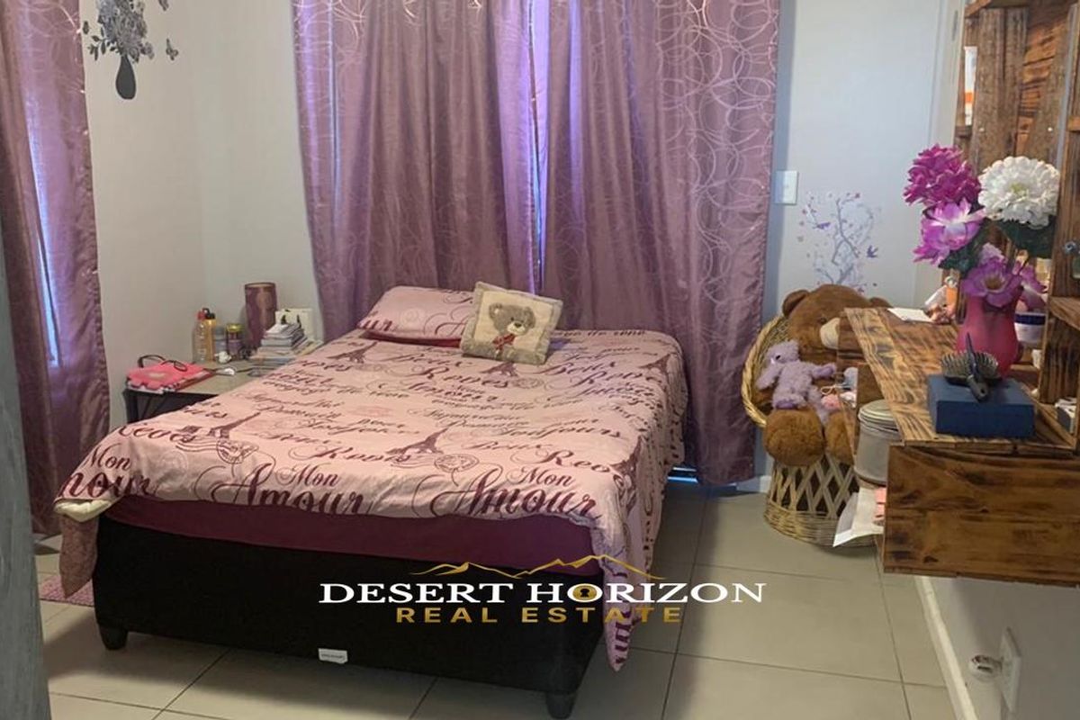 A bedroom featuring tiled flooring and built-in wall shelving.