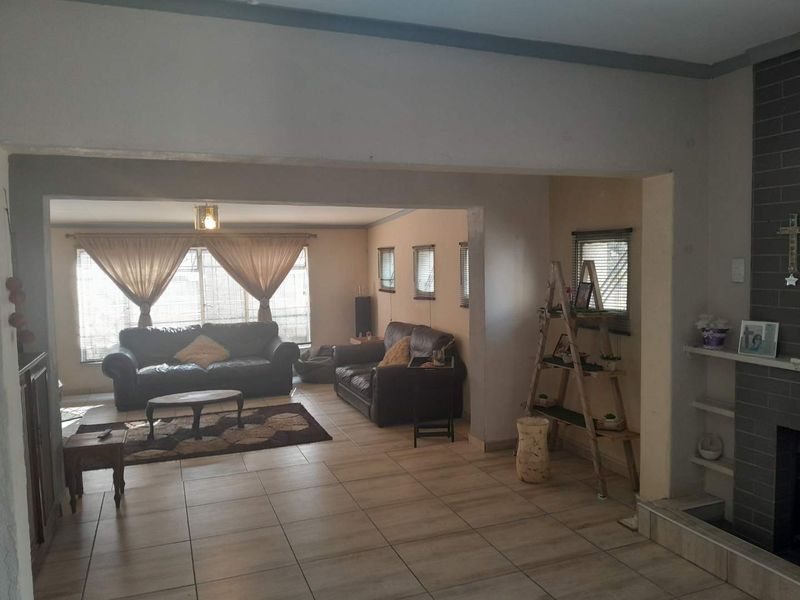Spacious open-plan living area featuring tiled flooring, a brick fireplace, and built-in shelving, offering a versatile layout for comfortable family living.