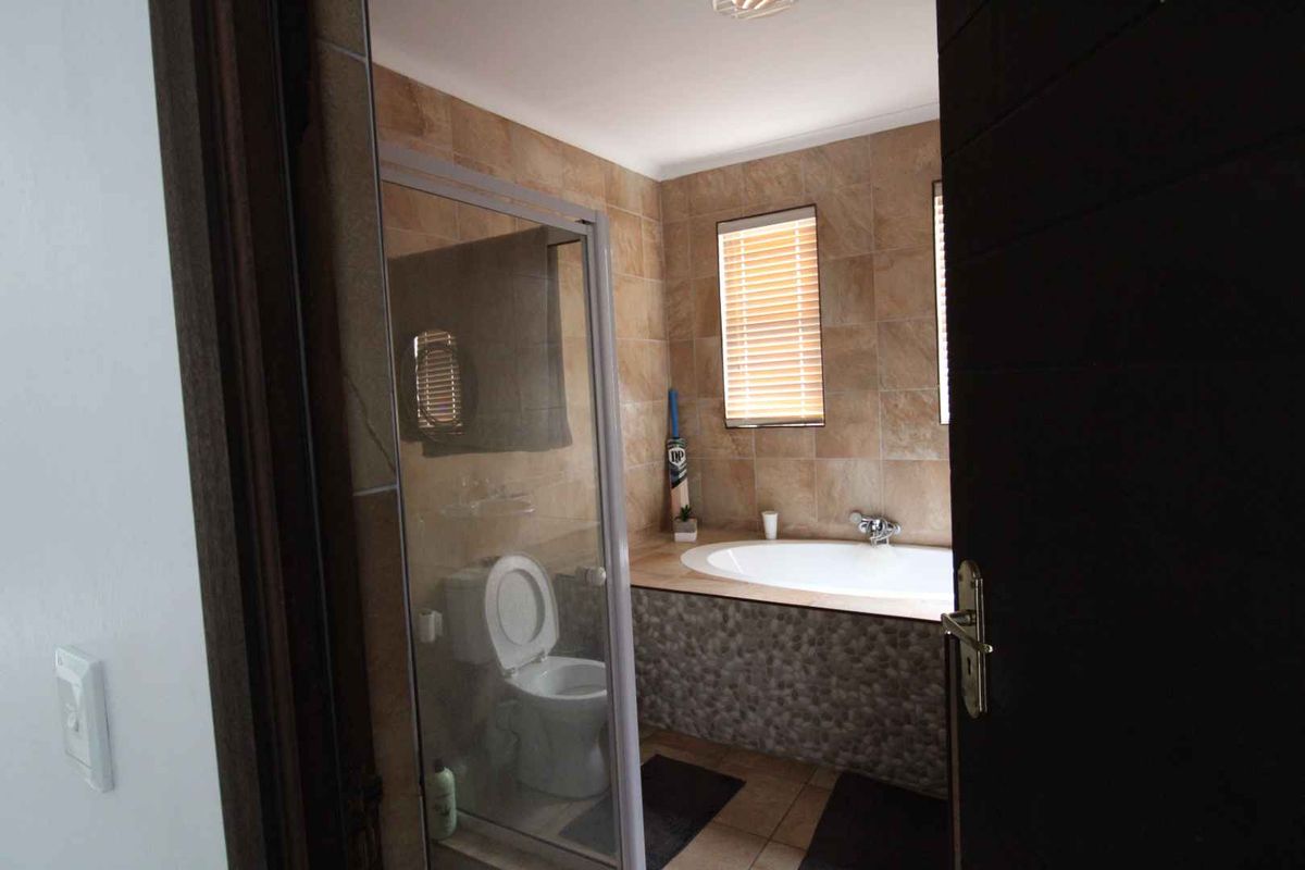 A bathroom featuring a built-in bathtub with tiled surround, a glass-enclosed shower, and neutral wall tiling.