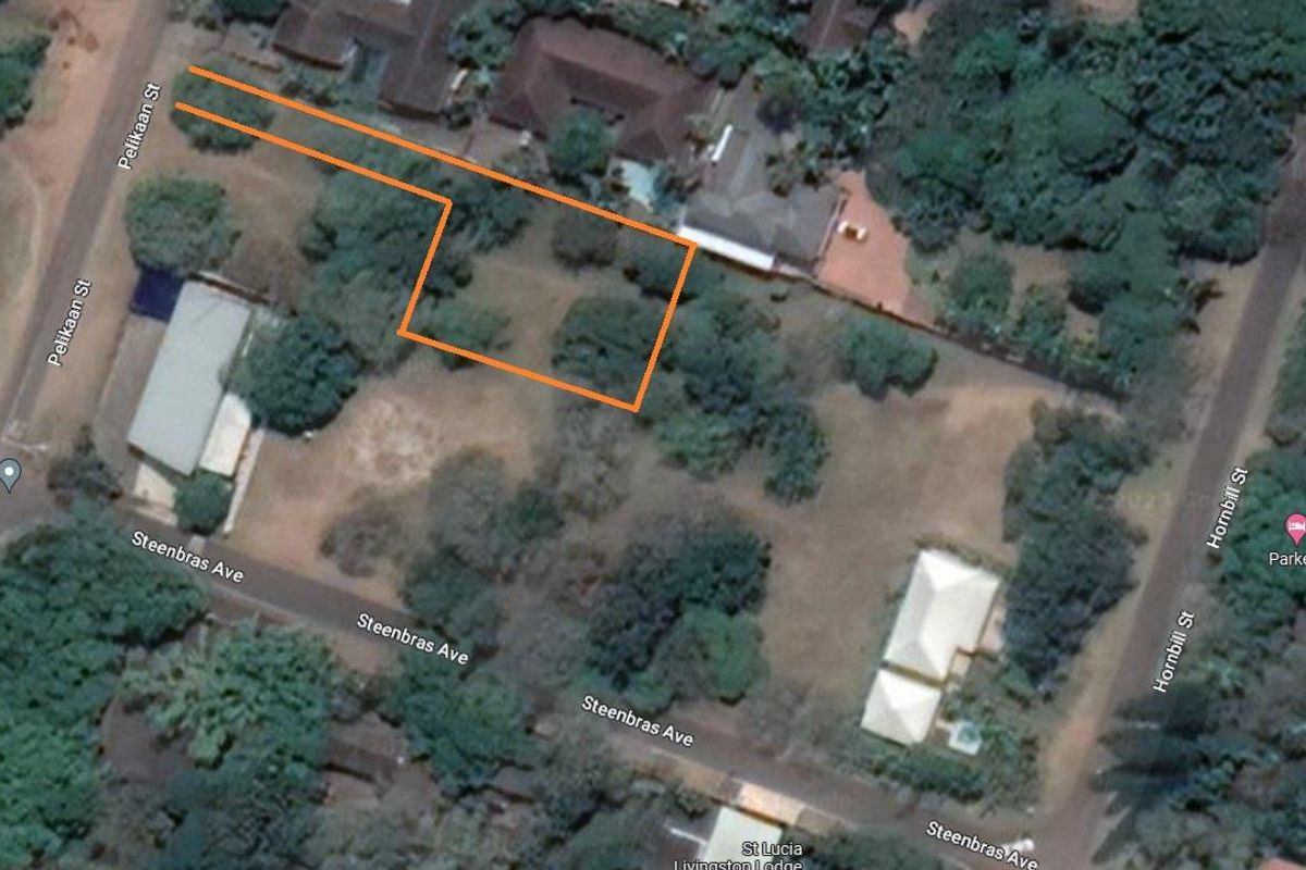 Aerial view of a vacant residential plot with established trees and vegetation, showing property boundaries and surrounding street access.