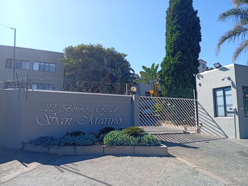 The entrance to San Marino apartment complex on Benmore Road, featuring a secure gated access point and perimeter walling.